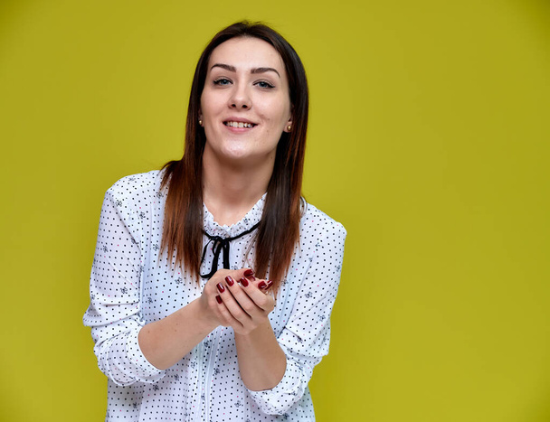 The concept of an office worker, teacher, manager. Portrait of a pretty brunette girl in a white business blouse smiling, talking to the camera on a yellow background. - Foto, immagini