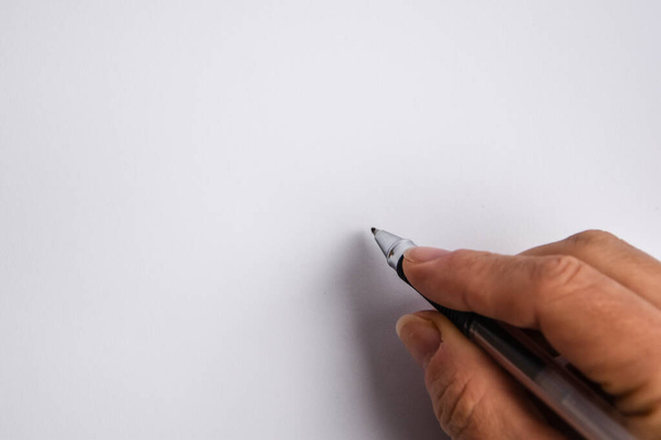 χέρι κρατώντας ένα στυλό και γράφοντας κάτι στο λευκό φόντο - Φωτογραφία, εικόνα