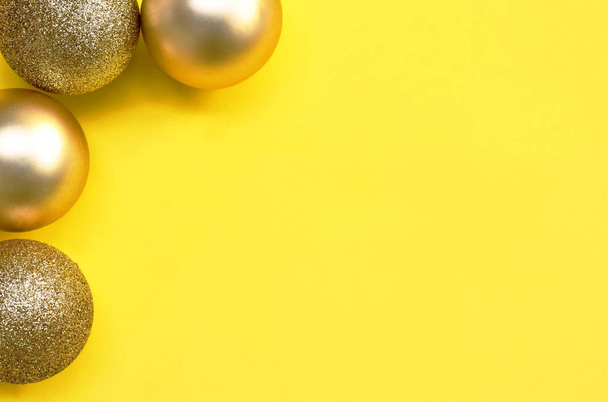  χρυσή μπάλα για διακόσμηση τα Χριστούγεννα και το νέο έτος φεστιβάλ σε κίτρινο φόντο - Φωτογραφία, εικόνα