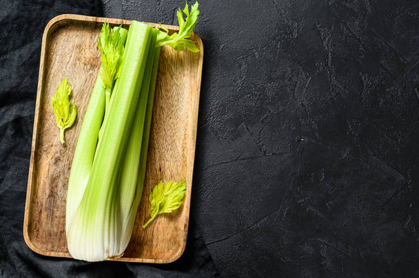 Bunch of fresh celery stalk with leaves. Black background. Top view. Space for text - Fotó, kép