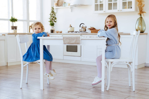 two children sitting on the kitchen table. - Fotoğraf, Görsel