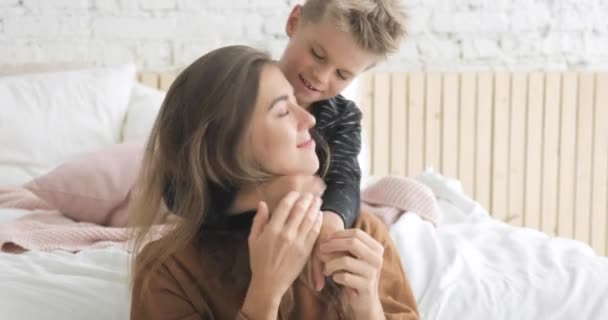 Portrait of mother and her little son cuddling in bedroom looking at camera. - Materiał filmowy, wideo