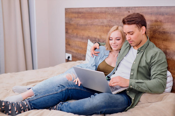cute woman and man lying on bed with laptop - Foto, Imagen