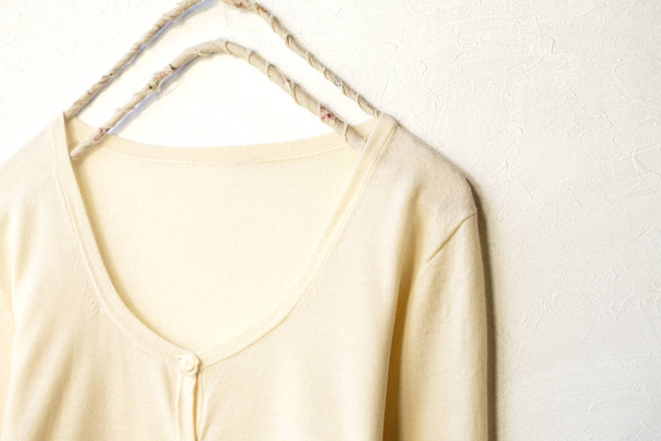a cardigan in white hanging on clothes hanger on white background. - Fotó, kép