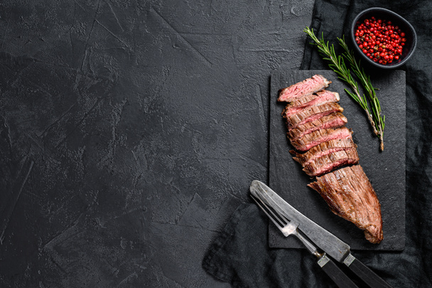 Steak de flanc de bœuf tranché moyen rare. Fond noir. Vue de dessus. Espace pour le texte
 - Photo, image