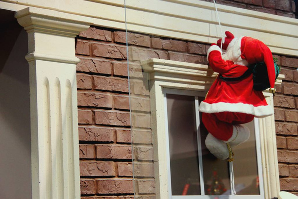 Santa Claus desciende en una cuerda. Decoración navideña de la fachada del edificio
 - Foto, imagen