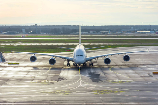 Vooraanzicht van een groot vliegtuig op stuursporen en parkeren op de luchthaven na de landing. - Foto, afbeelding