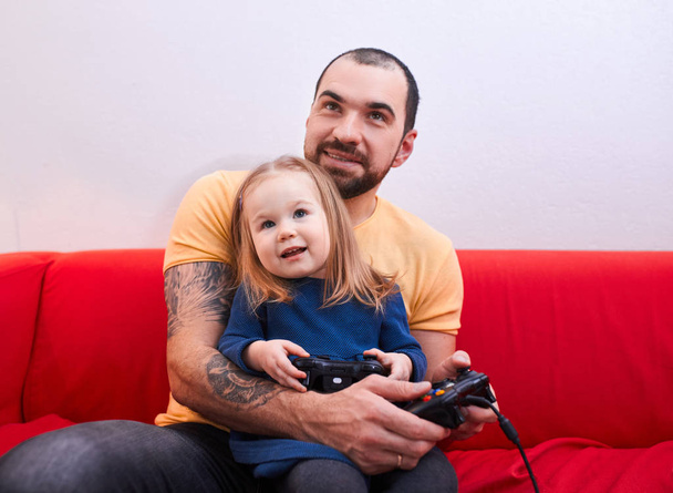 adorable child girl sit with father while he is playing video games - Фото, зображення
