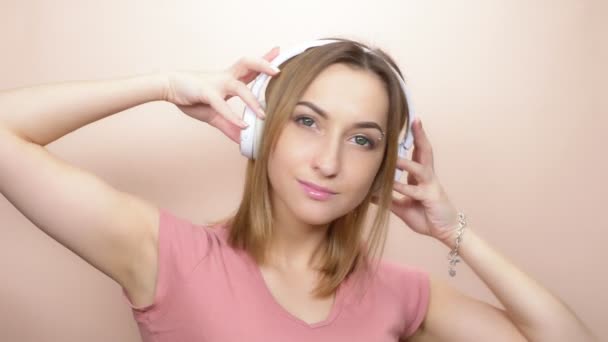 girl with pierced eyebrow and big eyes with headphones on a colored background - Filmati, video