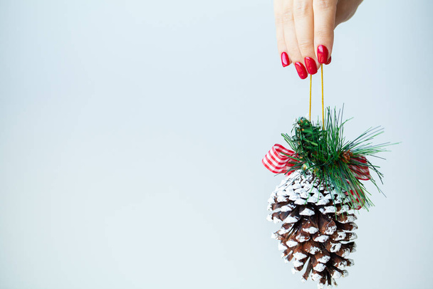Woman in hand holds Christmas decorations on light background - Photo, Image