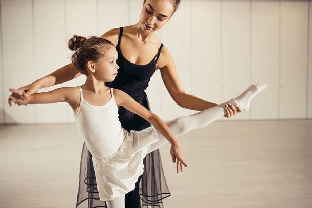 beautiful woman ballerina teaching little girl to dance classic ballet - Foto, immagini