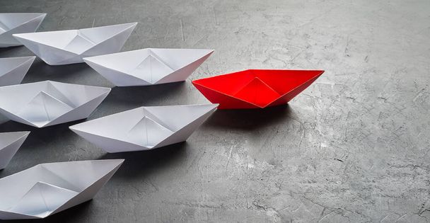 Business leadership Concept, Paper Boat, il parere chiave Leader, il concetto di influenza. Una barca di carta rossa come Leader, che conduce nella direzione delle navi bianche su uno sfondo grigio di cemento, c
 - Foto, immagini