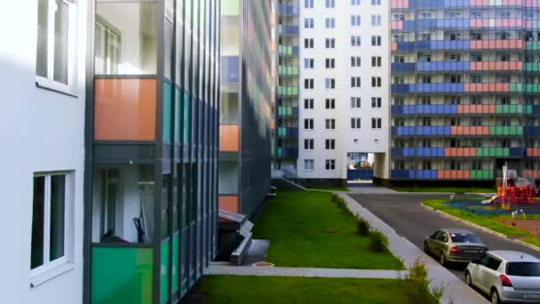 Aire de jeux colorée à l'intérieur de la cour entourée de nouvelles maisons résidentielles. Motion. Bâtiment lumineux avec balcons colorés et pelouse verte
. - Séquence, vidéo