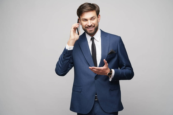 businessman talking on the phone isolated over grey background - Valokuva, kuva