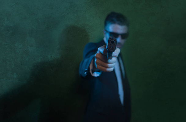 Man pointing handgun dramatic action portrait of attractive special agent or police officer aiming with gun in suit and tie holding the weapon serious in law enforcement - Foto, Imagem