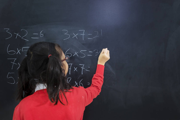 Back view of an adorable girl solving calculations - 写真・画像