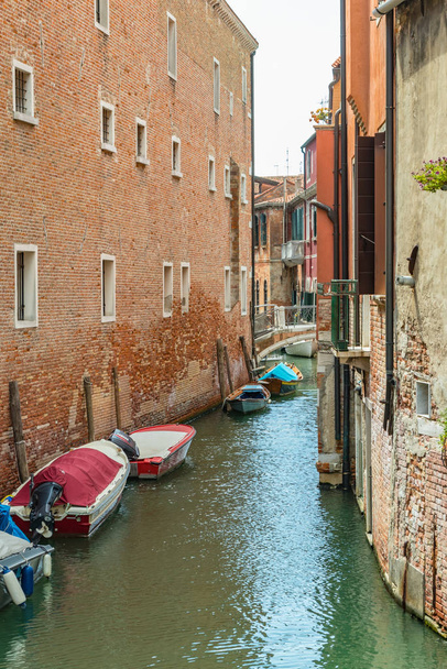 VENISE, ITALIE - 02 août 2019 : Un des milliers de beaux coins confortables de Venise par temps clair et ensoleillé. Les habitants et les touristes se promènent le long des bâtiments historiques et des canaux avec des bateaux amarrés
 - Photo, image