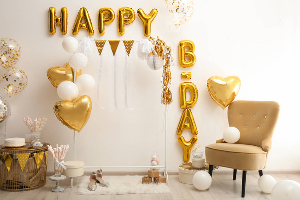 Phrase HAPPY BIRTHDAY made of golden balloon letters in decorated room - Φωτογραφία, εικόνα