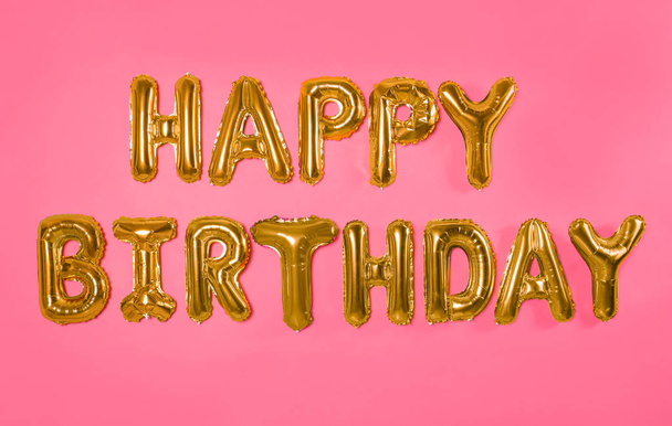 Phrase HAPPY BIRTHDAY made of foil balloon letters on pink background - Foto, Imagem