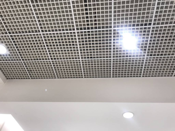石膏の天井のために描かれた白い絵付けされたエマルジョンとマクログリッド天井ショッピングモールの内部アーキテクチャの一時停止偽の天井のためのmuscatの男性の仕事 - 写真・画像