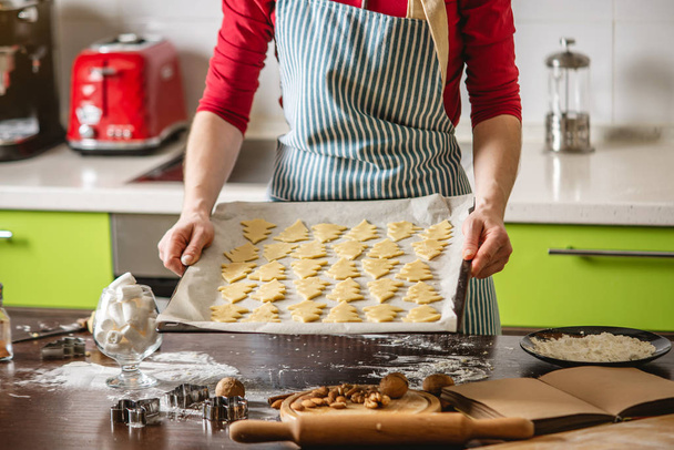 Kokki kotiäiti tekee joulun evästeet keittiössä. Nainen pitää leivinjauhetta taikinan muodossa joulukuusi - Valokuva, kuva