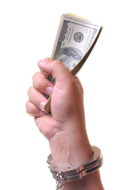 Mans hand in closed metal handcuff holding stack of american dollars - Фото, изображение
