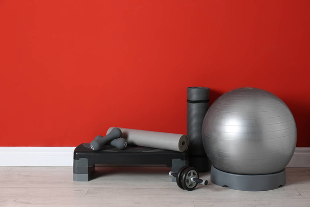 Different sports equipment near red wall in gym. Space for text - Foto, Bild