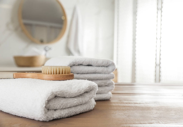 Empilement de serviettes propres et brosse de massage sur table en bois dans la baignoire
 - Photo, image