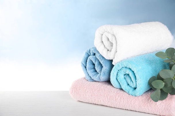 Rolled bath towels on white wooden table. Space for text - 写真・画像