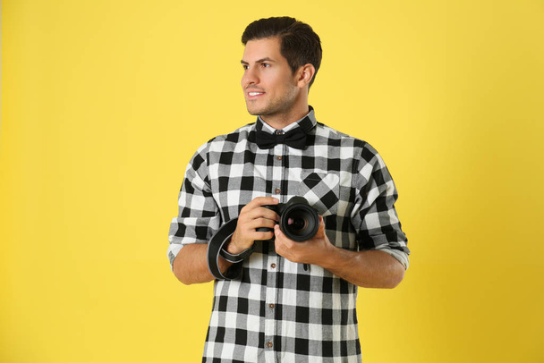 Professional photographer working on yellow background in studio - Zdjęcie, obraz