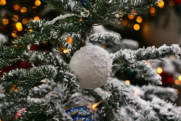 Christmas toy on a branch: silver ball, powdered with snow - Foto, Imagen
