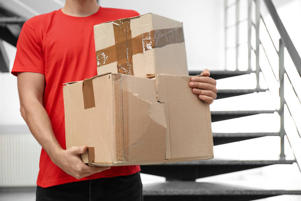 Courier with damaged cardboard boxes indoors, closeup. Poor quality delivery service - 写真・画像