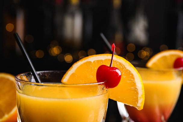 Fresh alcoholic Tequila Sunrise cocktail against blurred lights, closeup - Foto, afbeelding