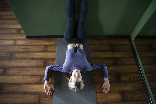 Young woman in yoga relaxing pose with legs up against wall, view from above - Photo, Image
