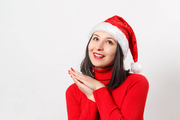 sweet dreamy young woman in a red sweater and Christmas hat. on white - 写真・画像