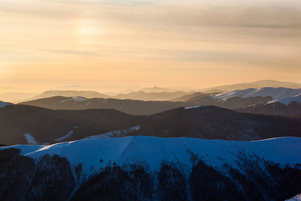 Sunset over mountains peaks covered with snow in winter clear day - Zdjęcie, obraz