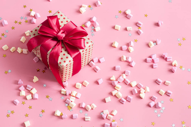 The concept of Valentine's day. Gift box with red bow on pink ba - Foto, Bild
