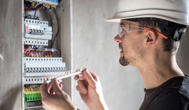 Hombre, un técnico eléctrico trabajando en una centralita con fusible
 - Foto, imagen