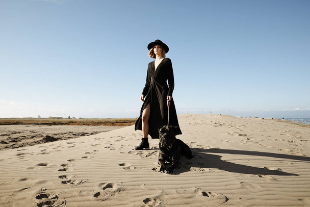 A woman standing on top of a sandy beach with dog. - Foto, Bild
