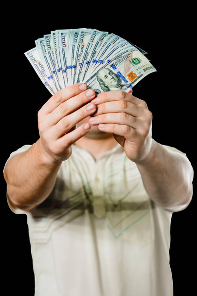 Close-up van de handen van een zakenman die geld over een zwarte achtergrond houdt. - Foto, afbeelding