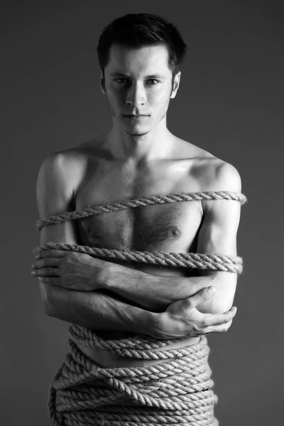 Portrait of young man with body tied up with ropes - Photo, image