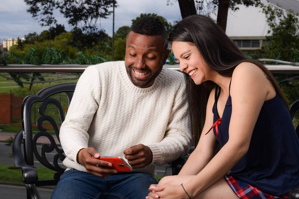 homem feliz e mulher verificando telefone celular sentado
 - Foto, Imagem