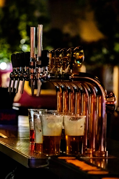 Pivní kohoutky v baru s vytočenými pivními brýlemi. Pivo. - Fotografie, Obrázek