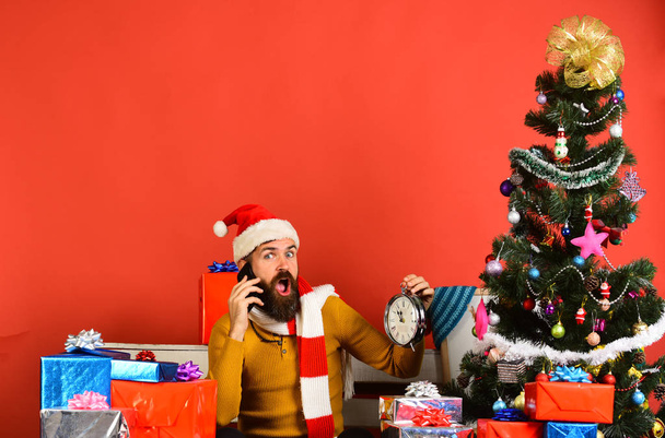Santa Claus talks on mobile phone near fir tree - Photo, Image