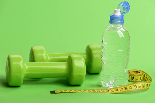 Barbells made of plastic near bottle of water. - Photo, Image