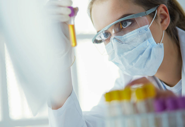 Portrait of pretty female laboratory assistant analyzing a blood sample at hospital - Photo, image