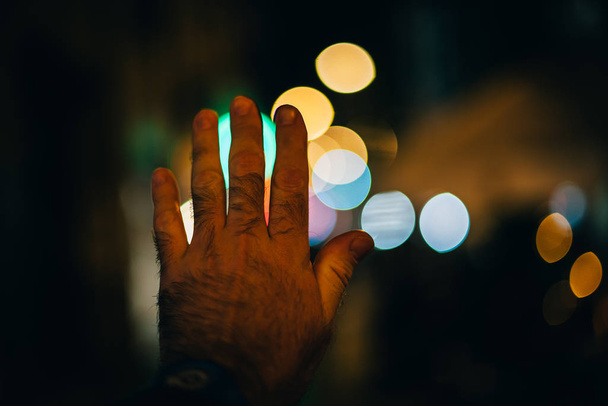 Άνθρωπος χέρι προσπαθεί να αγγίξει το φως bokeh - Φωτογραφία, εικόνα