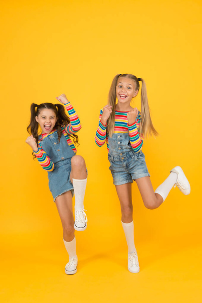 free and energetic beauty. happy childhood. real friendship. best friends forever. small sisters have fun. little girls jump yellow background. sense of freedom. finally summer vacation - Foto, immagini