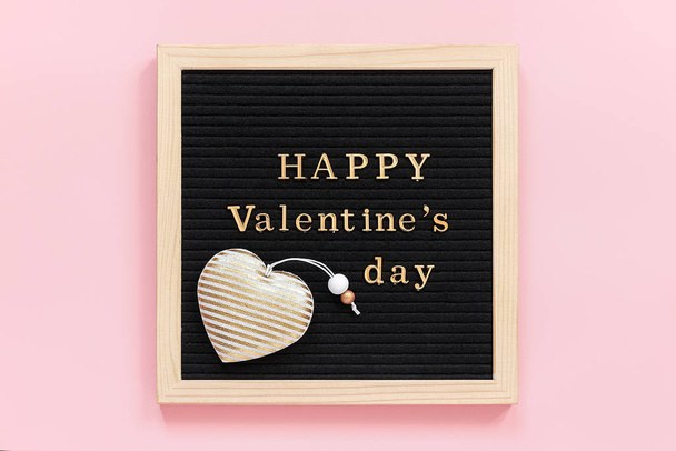 Złoty napis Szczęśliwe Walentynki i dekoracji tekstylne serce na czarnej tablicy, centralny skład na różowym tle. Szablon kartki walentynkowej, kartki okolicznościowej, pocztówki. Widok z góry - Zdjęcie, obraz