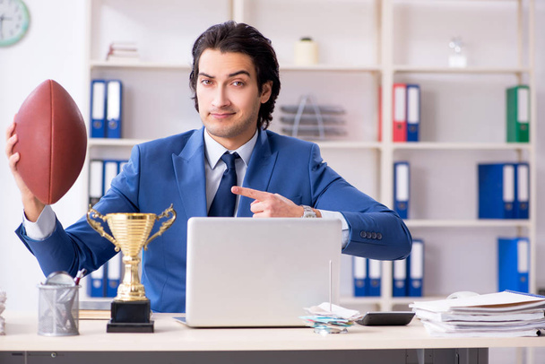 Jeune homme d'affaires beau avec ballon de rugby dans le bureau
 - Photo, image